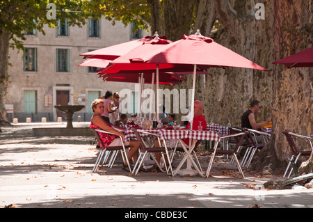 Les gens de prendre un verre sous les parasols sur une chaude journée d'été à la terrasse d'un café dans le centre-ville de Gignac Herault Banque D'Images