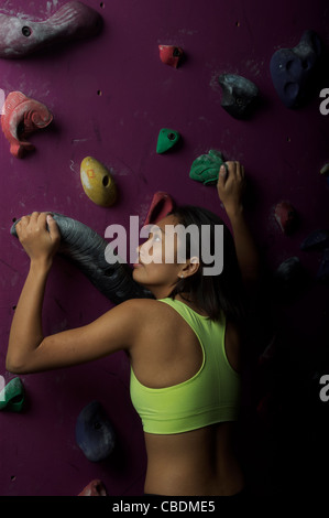 Jeune, athlétique et attrayant, l'escalade asiatique de la gir dans un centre artificiel d'escalade ou une salle de gym. Banque D'Images