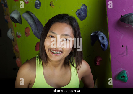 Jeune, athlétique et attrayant, l'escalade asiatique de la gir dans un centre artificiel d'escalade ou une salle de gym. Banque D'Images