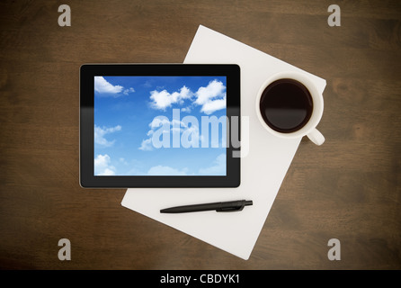 Tablette numérique avec des nuages sur l'écran posé sur table de travail avec papier, stylo et tasse de café. Notion de droit sur les cloud computing Banque D'Images