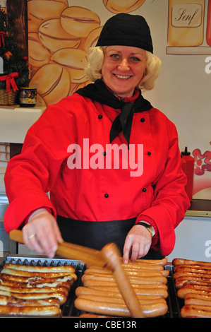 Femme travaillant au Marché de Noël de décrochage bratwurst, Rathausplatz, Hambourg, Hambourg, Allemagne Région métropolitaine Banque D'Images