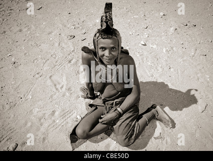 Femme Himba assis sur le sol, Iona Village, Angola Banque D'Images