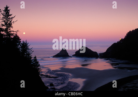 Le phare de Heceta Head et la pleine lune se couche sur l'océan ; Parc d'état de Devils Elbow, côte de l'Oregon. Banque D'Images