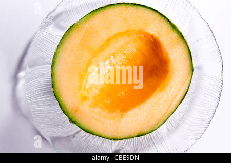 Un demi-cantaloup, coupé en deux, creusées dans les graines, assis sur une plaque de verre. Banque D'Images