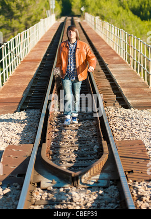 Musicien avec sa guitare sur le haut d'un pont de chemin de fer Banque D'Images