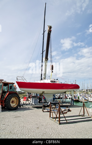 Bateau à voile de levage dans l'eau avec une grue dans le port Banque D'Images