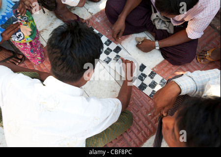 Les hommes assis jouant le jeu local avec des coquilles près de la Pagode Mahamuni, Mandalay, Myanmar (Birmanie). Banque D'Images