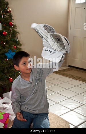 9-10 ans Hispanic American boy reçoit son rêve d'un but cadeau offres goaly Gant de hockey.Noël présent présente M. Pearson © Myrleen Banque D'Images