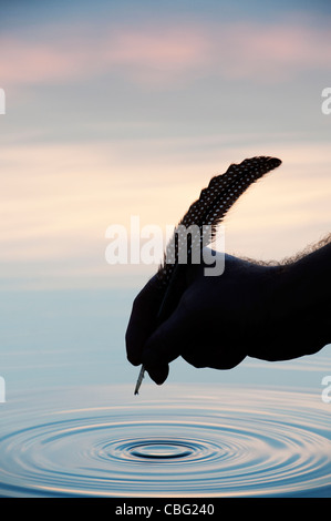 Main tenant au-dessus de l'eau de la douille avec silhouette d'ondulation Banque D'Images