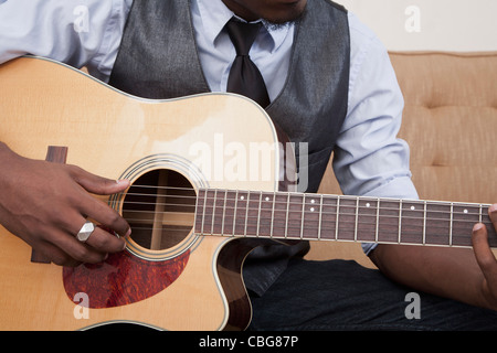 Un jeune homme jouant de la guitare acoustique, l'accent sur l'abdomen Banque D'Images