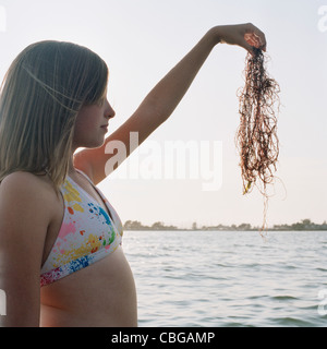 A teenage girl holding up seaweed Banque D'Images