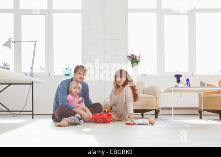 Une jeune famille jouer avec ses jouets sur le plancher du salon Banque D'Images