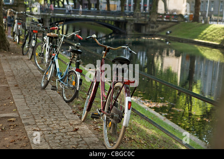 Cinq bicyclettes garées dans une rangée à côté d'une rivière Banque D'Images