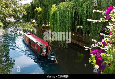 Barge à bateaux-Narrowboat Staycation avec croisière en famille sur la rivière Wey à travers Centre-ville de Guildford avec fleurs printanières en premier plan Surrey Angleterre ROYAUME-UNI Banque D'Images