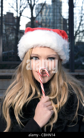 Un Caucasian woman holding une canne et portant un chapeau de Père Noël. Banque D'Images