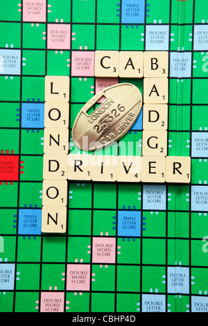 Badges des chauffeurs de taxi londoniens disposés sur une planche de scrabble. Père et fils étaient chauffeurs de taxi du début des années 70 à 2015. Banque D'Images