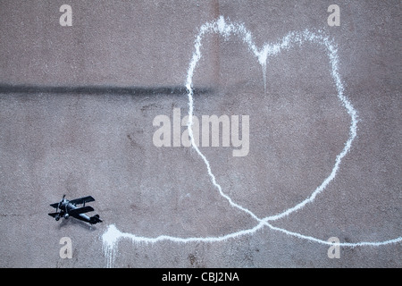 ' L'Amour Plane' Nouvelle art Bansky, l'on croit être la peinture par l'artiste de rue Banksy est apparue dans le centre-ville de Liverpool. Il représente un biplan laissant une traînée de fumée, est sur le mur à Rumford Street, Liverpool. La nuit semblait Dec 10th 2011. Banque D'Images