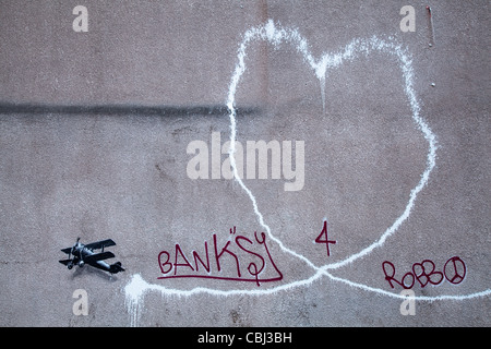 ' L'Amour Plane' nouveau art Bansky, l'on croit être la peinture abîmée par l'artiste de rue Banksy est apparue dans le centre-ville de Liverpool. Il représente un biplan laissant une traînée de fumée, est sur le mur de la région de Rumford Street, Liverpool. La nuit semblait Dec 10th 2011. Banque D'Images