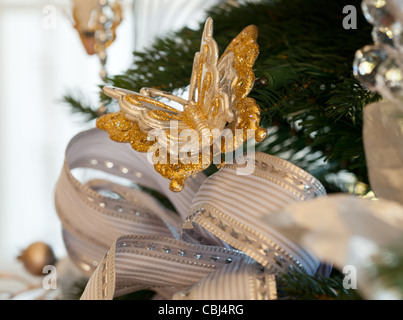 Arbre de Noël décoré d'argent et un ruban blanc et ornements papillon dans maison familiale Banque D'Images