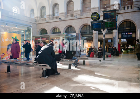 Les gens assis dans une zone d'attente dans la Gare de l'est de la gare ferroviaire de Paris, France. Banque D'Images