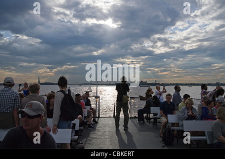 Ferry Statue de la Liberté et Ellis Island (en arrière-plan) les touristes sur le pont du bateau de retour à Manhattan après visite. Banque D'Images