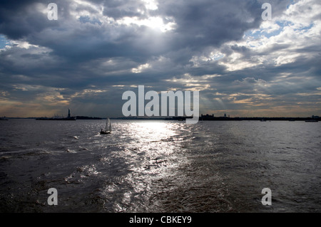 Panorama de la ville de New York Harbor sur une fin d'après-midi nuageux et silhouettes de Statue de la Liberté et Ellis Island à distance Banque D'Images