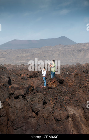 Touristes visitant Los Hervideros (les Boiling One), attraction touristique naturelle sur la côte où les coulées de lave du volcan solidifié ont été érodées par l'océan Atlantique entraînant wave.induced geysers, déversements et brume, Lanzarote, îles Canaries, Espagne. Banque D'Images