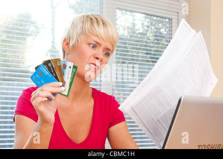 Femme choquée par des relevés de carte de crédit Banque D'Images