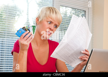 Femme choquée par des relevés de carte de crédit Banque D'Images