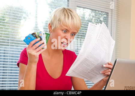 Femme choquée par des relevés de carte de crédit Banque D'Images