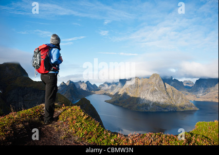 Female hiker bénéficie d'une vue spectaculaire sur les montagnes et les fjords du Reinebringen, îles Lofoten, Norvège Banque D'Images