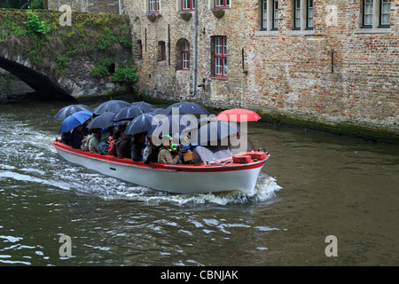 Les touristes dans un bateau avec tous les parapluies soulevées par temps humide. Un parapluie rouge au milieu des bleus. Banque D'Images