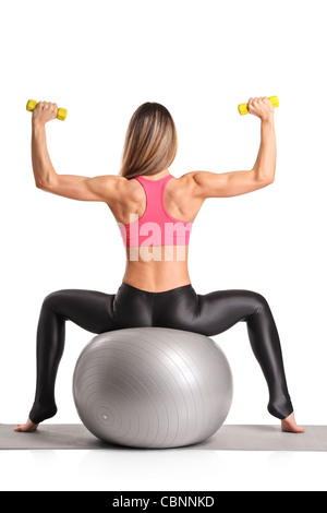 Une femme l'élaboration avec les cloches sourdes-muettes, assise sur un ballon pilates Banque D'Images