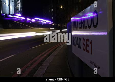 Une soirée coup de light trails à partir d'une voiture de police passant un "Waterloo Road" road sign in London, England Banque D'Images