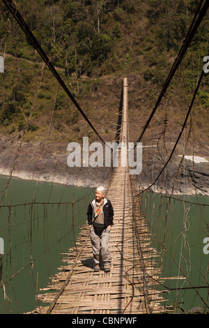 L'Inde, de l'Arunachal Pradesh, Kabang, contreforts de l'Himalaya, femme occidentale traversant pont suspendu au-dessus de la rivière Siang Banque D'Images