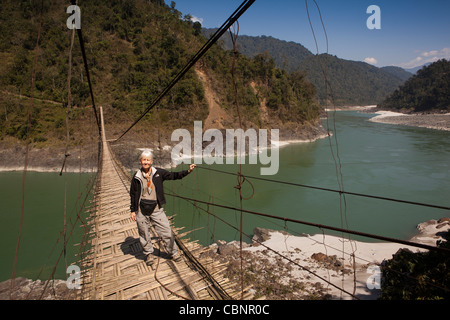 L'Inde, de l'Arunachal Pradesh, Kabang, contreforts de l'Himalaya, femme occidentale traversant pont suspendu au-dessus de la rivière Siang Banque D'Images