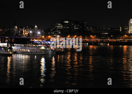 Rivière Thames dans la nuit avec un quai de fête à l'avant-plan et Hungerford Bridge en arrière-plan, Londres. UK. Banque D'Images