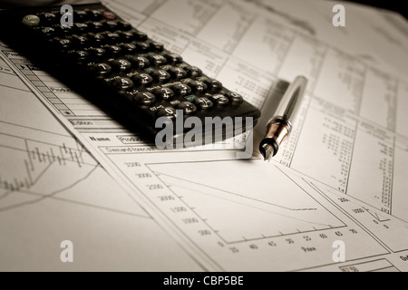 Graphiques et tableaux financiers allongé sur la table avec la calculatrice et stylo Banque D'Images