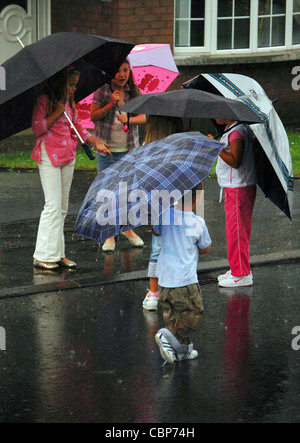 Les jeunes enfants des parasols dans heavy rain, Londonderry, en Irlande du Nord, Royaume-Uni Banque D'Images