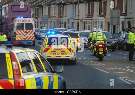 Plusieurs véhicules de police avec feux bleus traverser une ville carrefour au cours de match de football de contrôle de foule. Portsmouth Hampshire. Banque D'Images