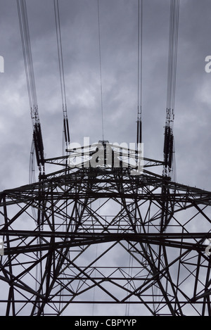 Silhouette d'électricité pylône situé contre un ciel nuageux Banque D'Images