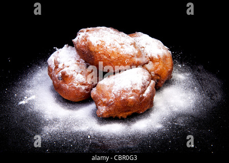 Pile de Dutch donut aussi connu sous le nom de oliebollen avec du sucre en poudre, la veille du Nouvel An traditionnel isolé de l'alimentation sur fond noir Banque D'Images