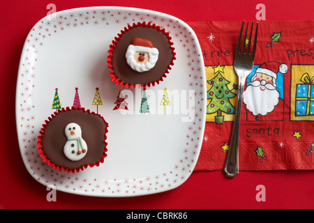 Le Snowman cupcake cupcakes et Santa des gâteaux sur la plaque de l'arbre de Noël et Noël serviette avec fourche sur fond rouge Banque D'Images
