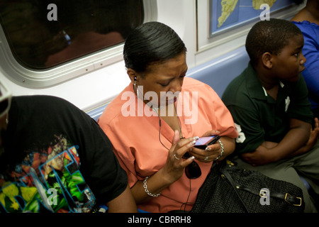 Une femme afro-américaine à l'écoute de la musique tout en prenant le métro de la ville de New York le 29 juin 2011. Banque D'Images