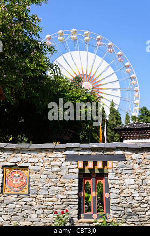 Fenêtre Bois & Pierre & sculpture en mur de pavillon du Bhoutan à l'expo avec une immense roue de Ferris en arrière-plan de Chiang Mai en Thaïlande. Banque D'Images