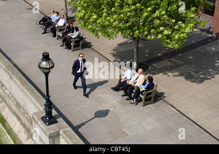 Pause déjeuner pour les employés de bureau sur la Tamise promenade côtière ci-dessous Millenium Bridge, Blackfriars, London, UK Banque D'Images