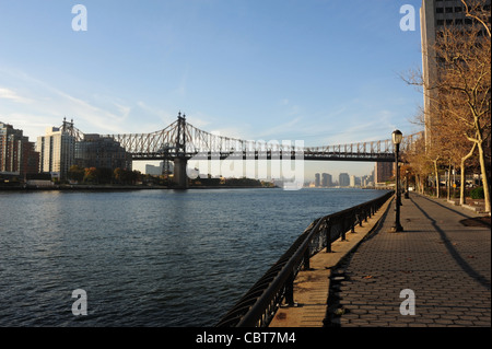 Ciel bleu, les arbres d'automne voir l'allée de l'Esplanade de la rivière East, eaux bleu chenal West East River à Queensboro Bridge, New York Banque D'Images