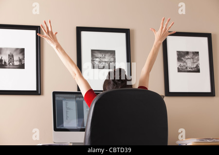 Caucasian woman cheering at desk in office Banque D'Images