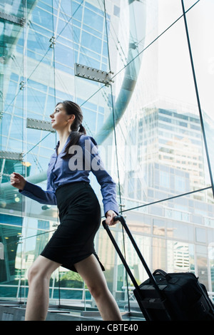 Caucasian businesswoman pulling suitcase en plein air Banque D'Images