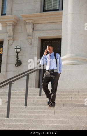 Black businessman talking on cell phone et descendant des escaliers Banque D'Images